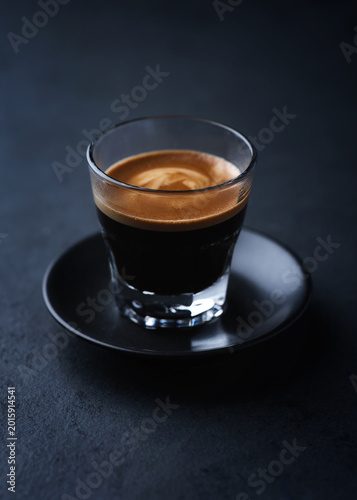 Coffee in glass cup on a dark stone background. Soft focus. Close up. Copy space.