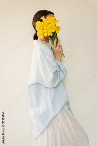 Side Profile Of An Anonymous Person Holding Fresh Spring Narcissus Flowers In A Bright Studio