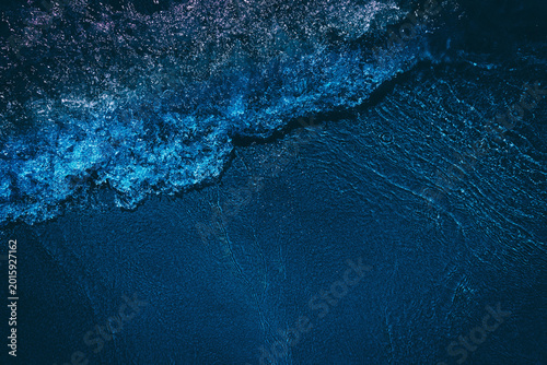Wave on dark blue sand beach 