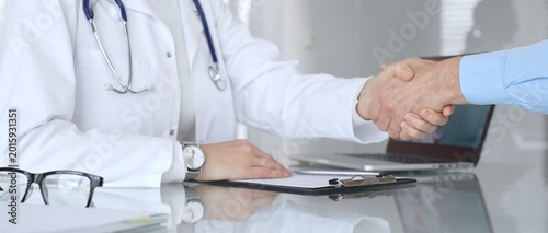 Photos Doctor and patient handshaking, establishing trust and agreement during medical consultation in hospital setting