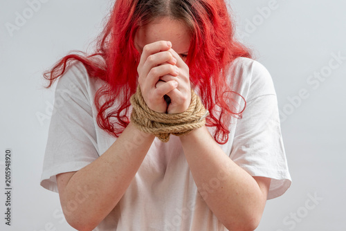 Cuadro en lienzo Close-up of female victim with wrists tied by rope, head down in distress, concept of abduction, human trafficking, coercion, abuse and crisis