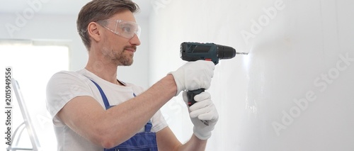 Fotografie Man professional construction worker in a blue jumpsuit, safety goggles, and wor