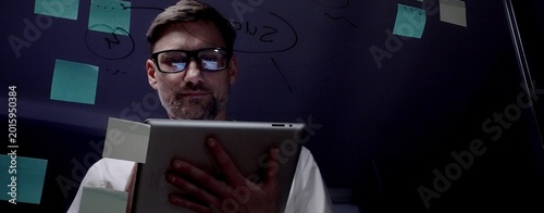 Man in eyeglasses organizing thoughts and ideas for business optimization on a clear glass board. Creating a strategic roadmap for innovation and project planning