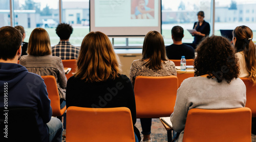 Diverse group of adults attend workshop. Speaker presents information on projector screen. People learn, engage, and discuss in classroom setting. New parents gather for advice.