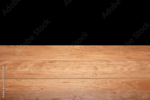 A long, solid cherry wood tabletop against a black background. Wooden tabletop background. Cherry wood grain.