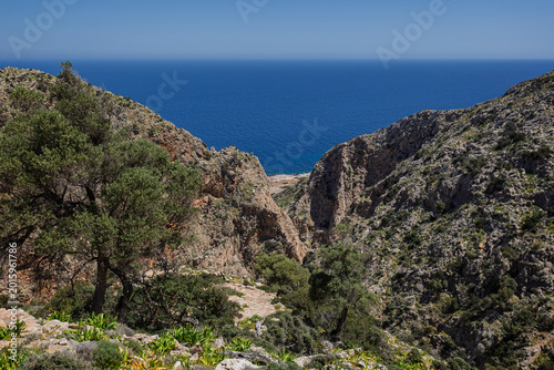 Fotografie Rugged, steep and rocky cliffs by the Sea of Crete along the Katholiko (or Avlaki) Gorge hike in Crete, Greece, on sunny day, viewed from above
