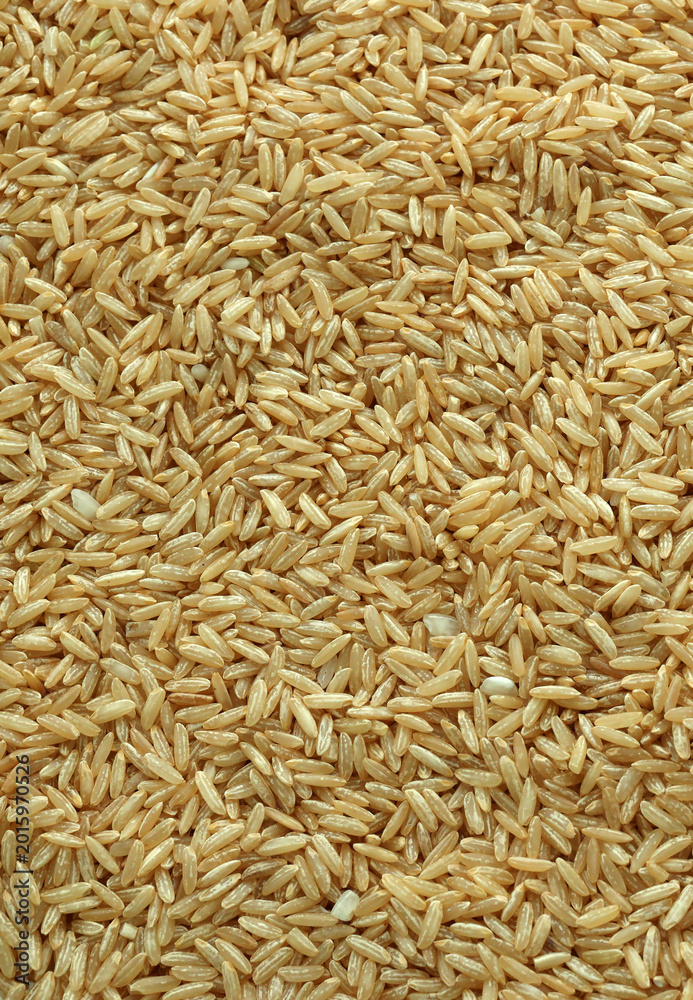 Fototapeta premium Dry brown rice grains in big pile on table close up. Large amount of brown rice seeds