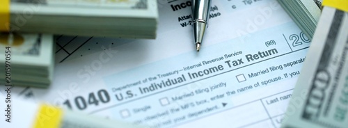 Photos 1040 Individual Income tax return form and hundred dollars money bills packs on
