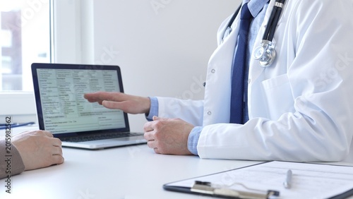 Doctor reviewing digital test results with patient, discussing health findings on laptop screen during clinical consultation. Medicine and health care concept.