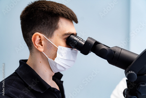 Fotografie Male stomatologist using high precision microscope for dental surgery