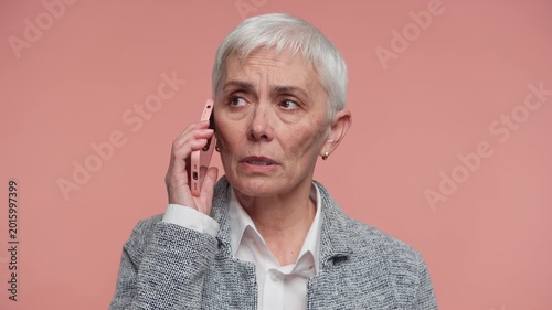 Senior Woman Having Serious Phone Call on Pink Background