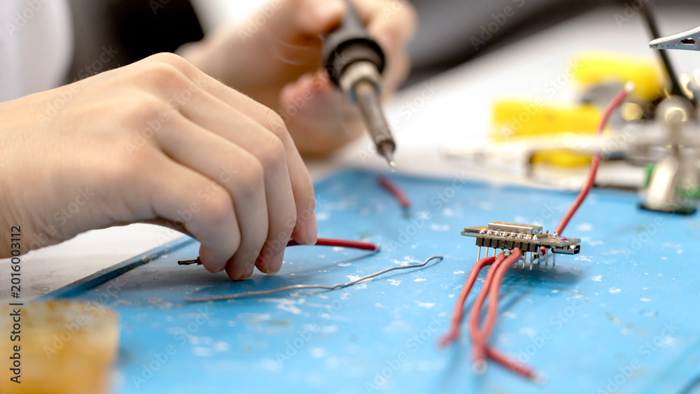 Obraz premium Hands steady wires on a blue workbench