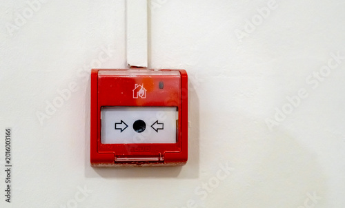 Red fire alarm device mounted on white wall