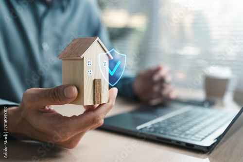 Foto Hand holding wooden house with shield icon, representing home insurance, property protection, mortgage security, risk coverage and financial safety for homeowners