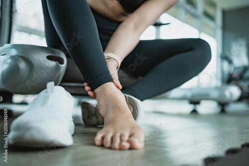 Bild auf Leinwand Asian fitness woman holding painful ankle after workout in gym