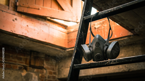 Gas mask hanging on a ladder in dusty abandoned building  