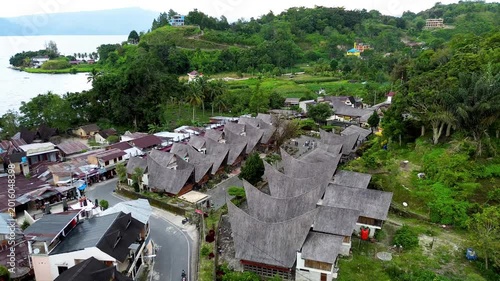 Drone aerial of Batak traditional architecture and green hillside in Samosir Lake Toba