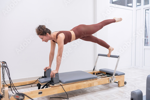 Foto Pilates reformer woman performs a core strengthening exercise in a bright modern