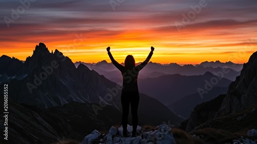 A silhouette celebrating at sunset over majestic mountains.