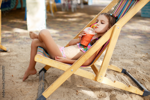 Konstfotografi A little girl on the beach with a cocktail in her hands