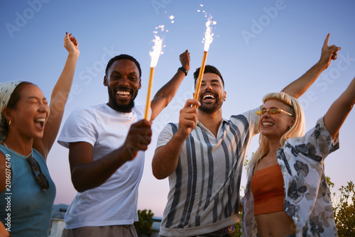 Fotografie Young friends celebrating together with sparklers during rooftop gathering