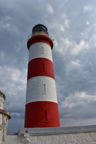 Obraz na plátně Thick Cloudy Skies Surrounding a Striped Lighthouse