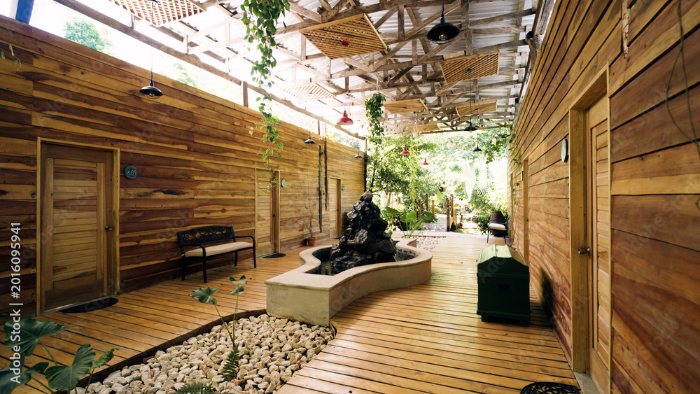 Fototapeta premium Sustainable architecture and natural design blending a tropical resort with nature. Featuring wooden walls, decking, and a stone fountain