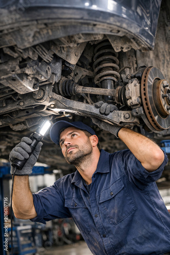 Auto mechanic repairing vehicle's shock absorbers and springs