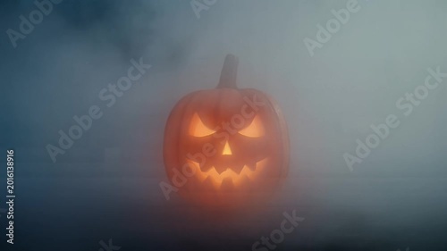 Glowing Halloween Jack O Lantern Pumpkin in Spooky Foggy Night.