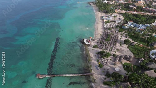 Aerial view of a tropical beach with turquoise water,white sand beach,palm trees,lighthouse and wooden pier, la Romana, Dominican republic.
