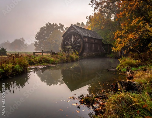 Old wooden mill by misty water, autumn trees