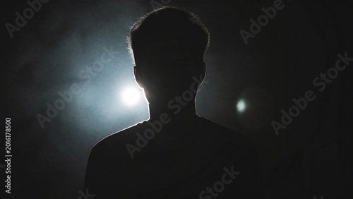 A silhouette in dim light with a faint glow, creating a mysterious and atmospheric mood.