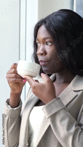 Professional Contemplates Cityscape Tranquility. Businessperson With Mug Observes Peaceful City Morning Scene. An Executive Dressed Formally Sips Coffee While Reflecting On Serene Cityscape View