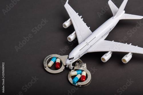 Tableau sur toile Passenger airplane with handcuffs and drug capsules representing international drug trafficking, airport crime, aviation security, customs inspection, smuggling, and illegal transportation concept