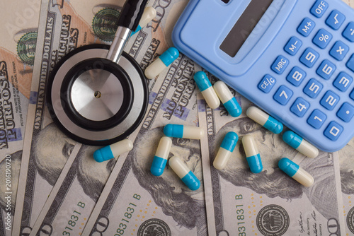 Stethoscope, calculator, medicine capsules, and dollar bills illustrating healthcare expenses, medical insurance, pharmacy costs, and financial planning concept.