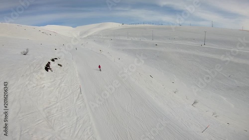 Single Skier Over Icy Terrain. Flyover Shot Of Snow Field With Solitary Skier On Gentle Ascent. Aerial Perspective Reveals Expansive Snowcovered Terrain With One Skier Traversing Gentle Inclines