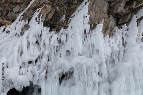 Canvas Print Close-up of frozen icicles and layered ice formations hanging from a rocky cliff