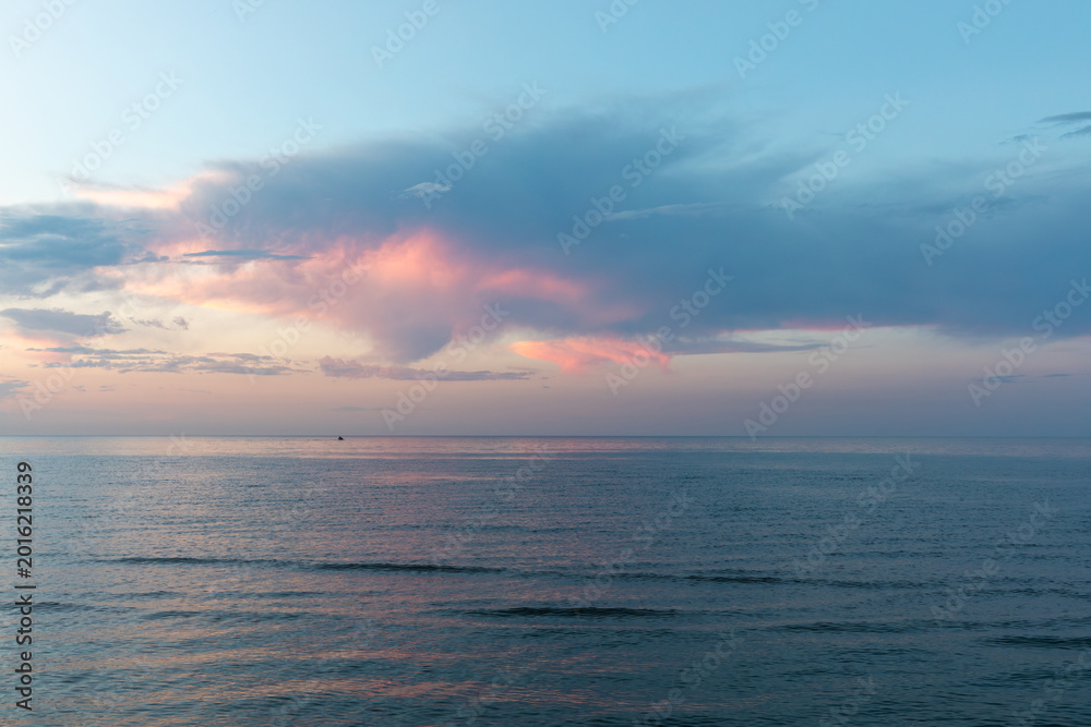 Fototapeta premium Serene seascape at sunset on the Caspian Sea near Derbent, Republic of Dagestan, Russia, with pastel pink clouds, calm water, and a wide open horizon