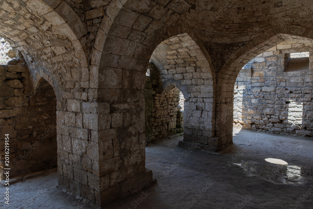 Fototapeta premium Interior view of ancient stone vaults and arches in Naryn-Kala fortress, Derbent, Republic of Dagestan, Russia, with sunlight and shadows on old masonry