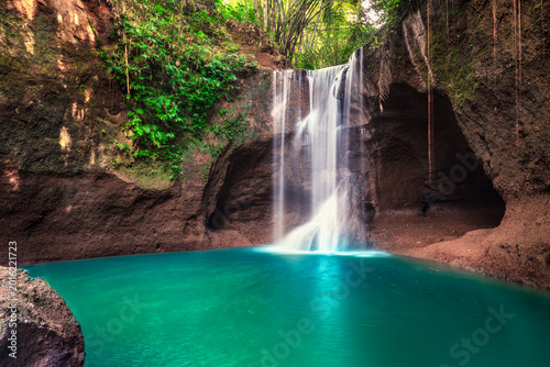 Tropical rainforest waterfall in the jungle landscape. Palm trees pond misty morning flowers and tropics.
