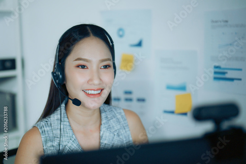 Schilderij op canvas Customer service woman with headset talks at computer in office, showing online support and call center work