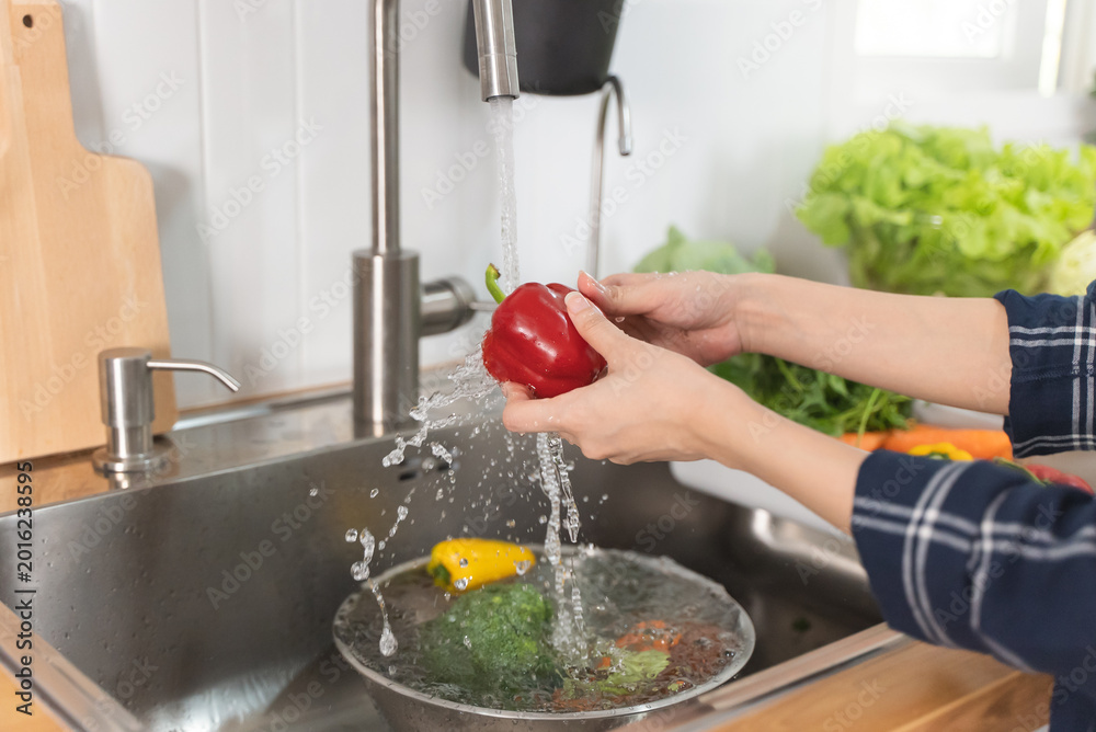 Fototapeta premium Close up of hands people washing vegetables by tap water at the sink in the kitchen to clean ingredient prepare a fresh salad.