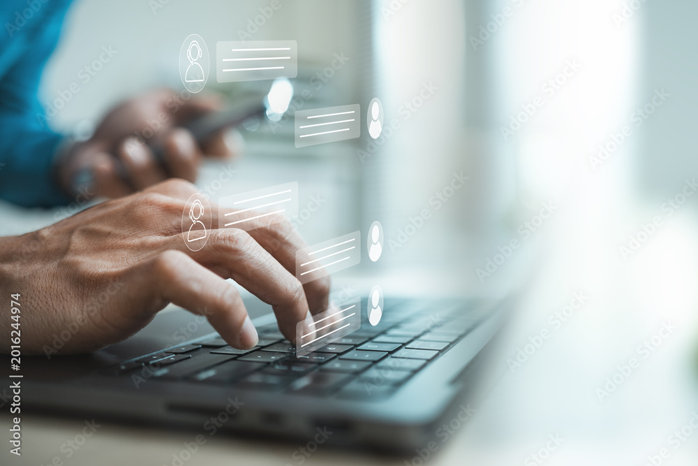 Fototapeta premium Customer support agent using laptop with virtual live chat interface, representing online assistance, instant messaging, CRM service, AI chatbot communication, help desk response.