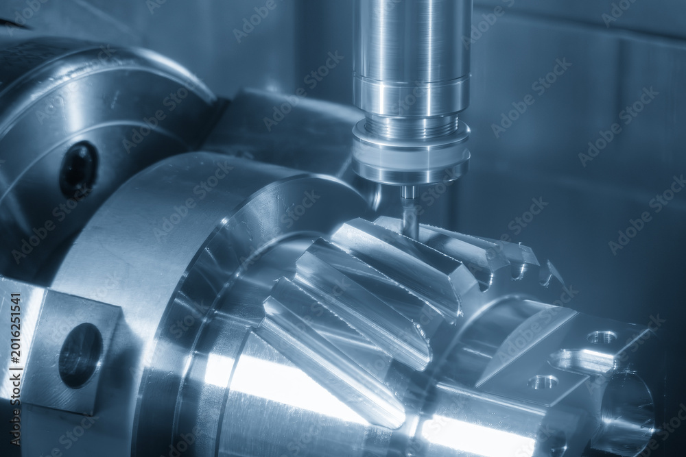 Fototapeta premium Advanced 5-axis CNC milling machine cutting a complex bevel gear shape on a transmission gear shaft.