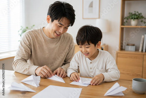 Father and son making paper airplanes together at home