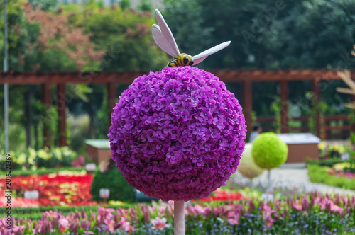 A fake bee on a purple flower topiary in a garden in macau china on a sunny day.