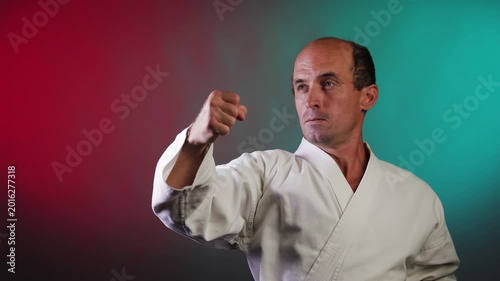 A young athlete blocks and punches against a multi-colored background with flashing red and green lights