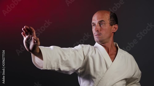 A young athlete makes roundhouse punches and blocks with his fist and hand against a multi-colored background with flashing red and green lights