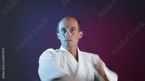 A young athlete performs blocks and punches against a multi-colored background with flashing lights