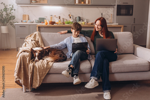 Full length shot of happy family and their dog relaxing with digital devices at home
